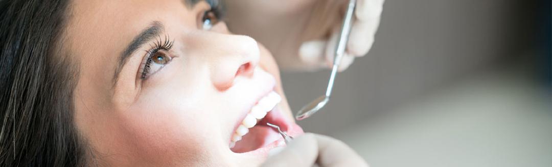 A young woman is at the dentist getting her teeth checked to prevent gum disease
