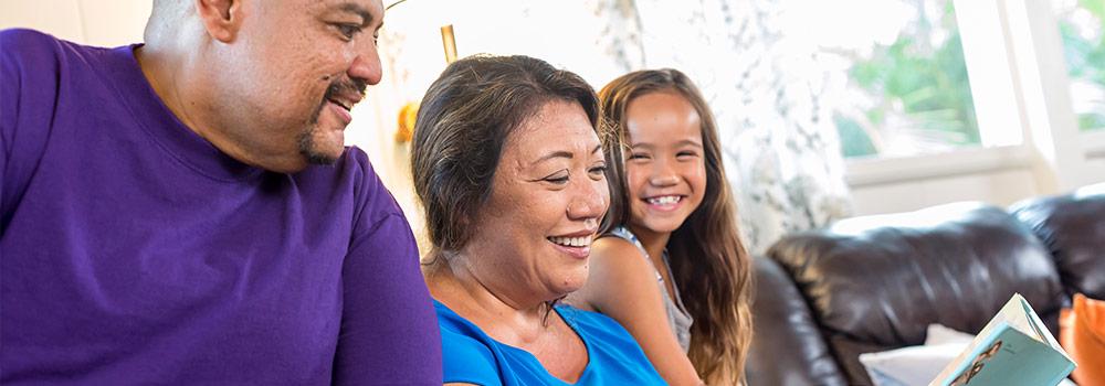 Hawaiian grandparents are shown at home visiting with their granddaughter
